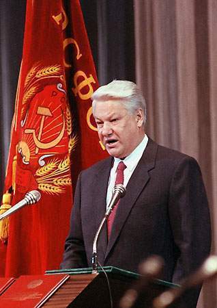 Fotografía de Boris Yeltsin, presidente soviético y ruso, hablando en un atril, con bandera soviética de fondo