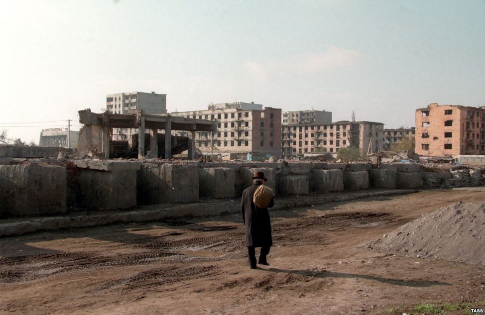 La capital de la República de Chechenia, Grozni, en ruinas. Un hombre camina con una bolsa al hombro.