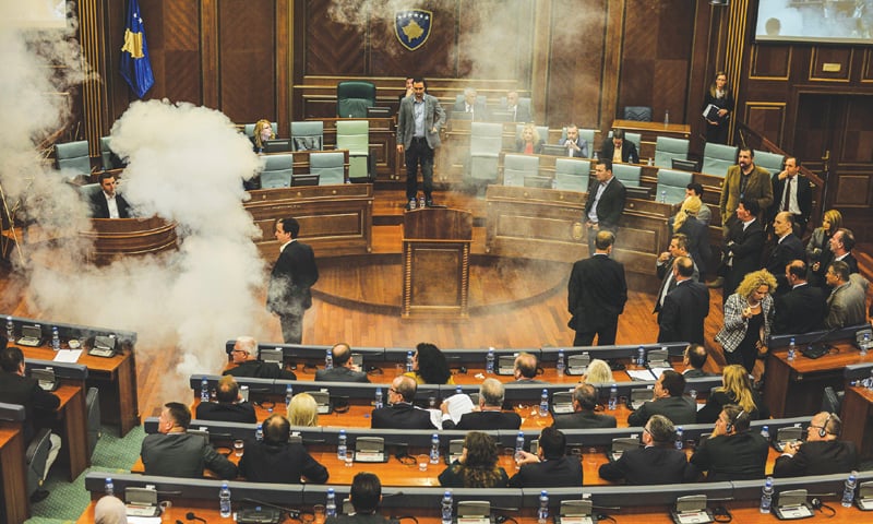 Miembros del partido VV en 2018, en la oposición, lanzan gases lacrimógenos en el parlamento de Kosovo por el acuerdo con Montenegro