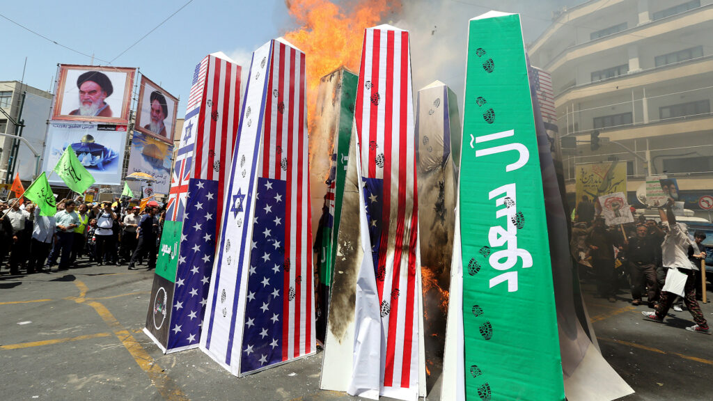 Manifestantes iraníes queman la bandera de Estados Unidos, Reino Unido, Israel y una pancarta con la frase "Familia Saud" escrita en referencia a Arabia Saudí