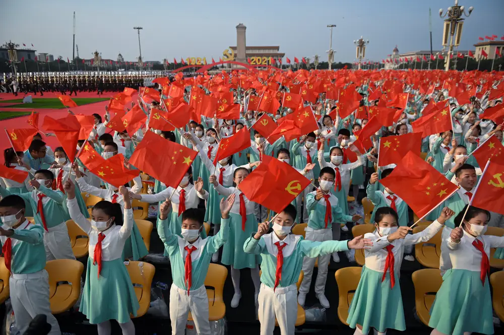 Estudiantes ondean banderas chinas para celebrar el centenario de la fundación del Partido Comunista de China en la Plaza de Tiananmen en Pekín