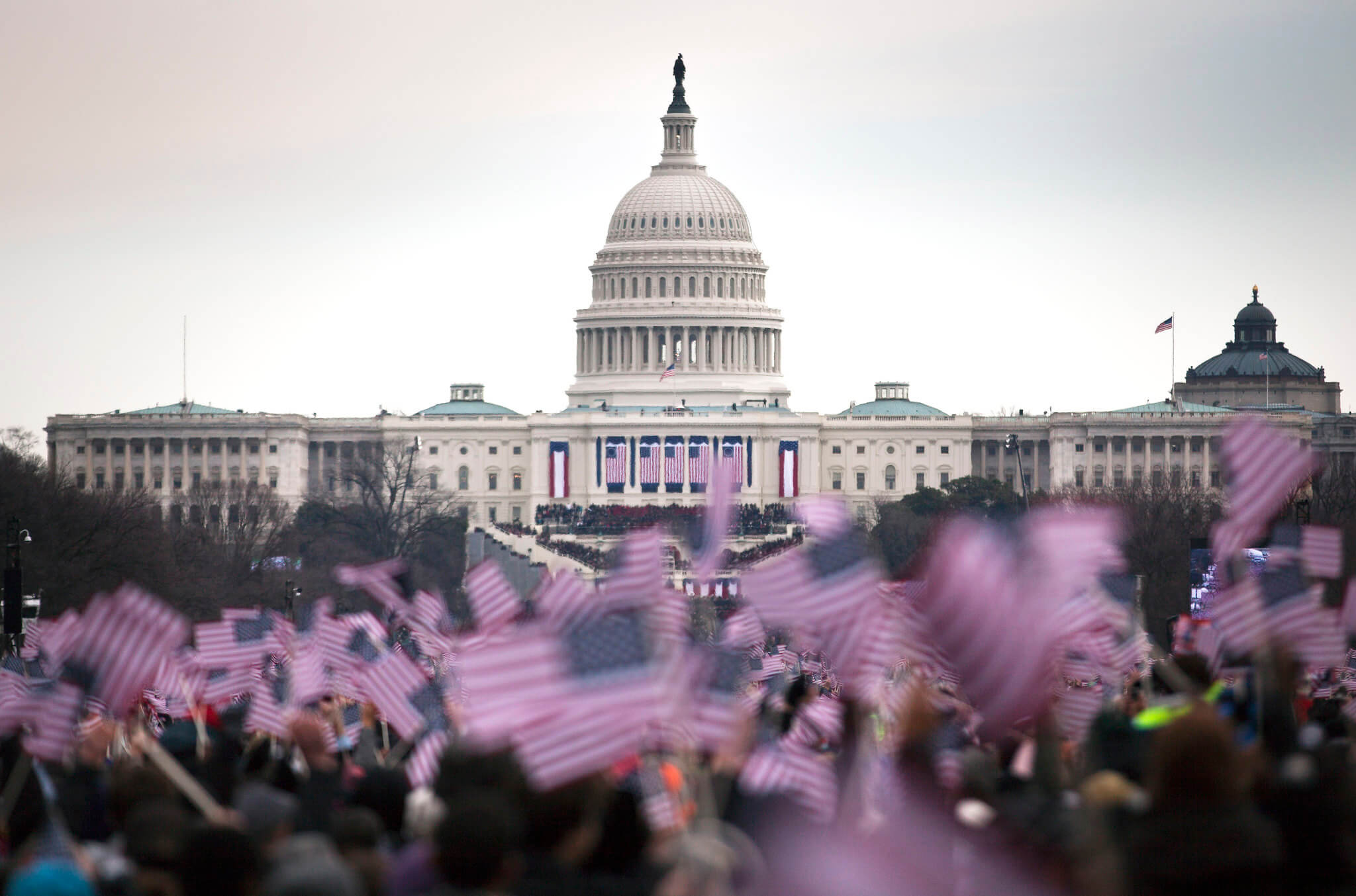 Decenas de personas ondean banderas de Estados Unidos frente al Capitolio, en Washington DC