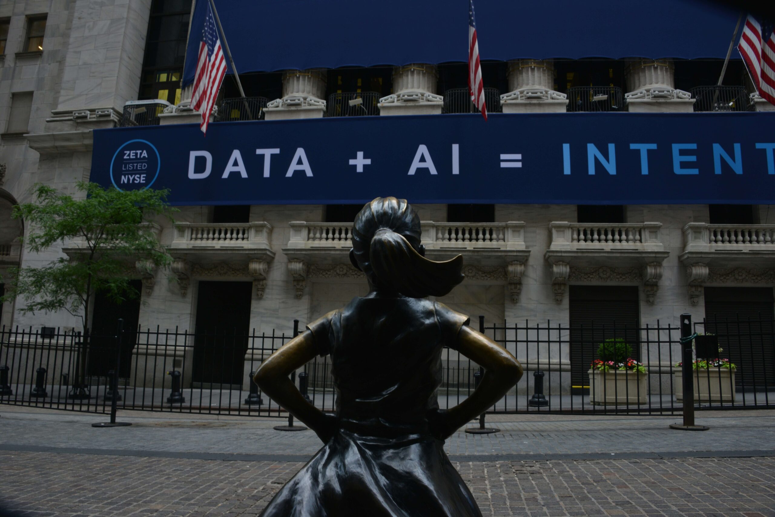 Estatua de la 'Niña sin miedo' frente a un Wall Street que abraza la incorporación de la Inteligencia Artificial.